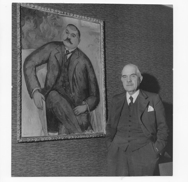 Axel F Enström stående framör ett målat porträtt av sig själv