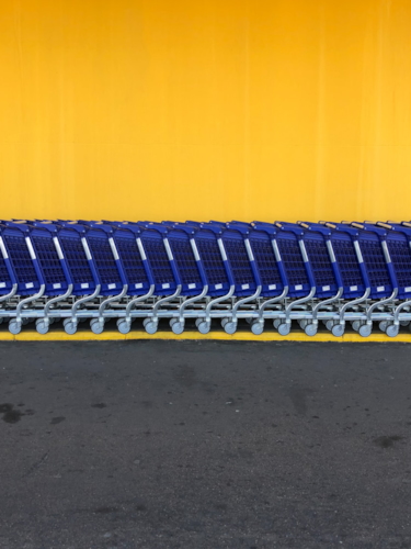 Empty blue shopping trolleys lined up against yellow wall