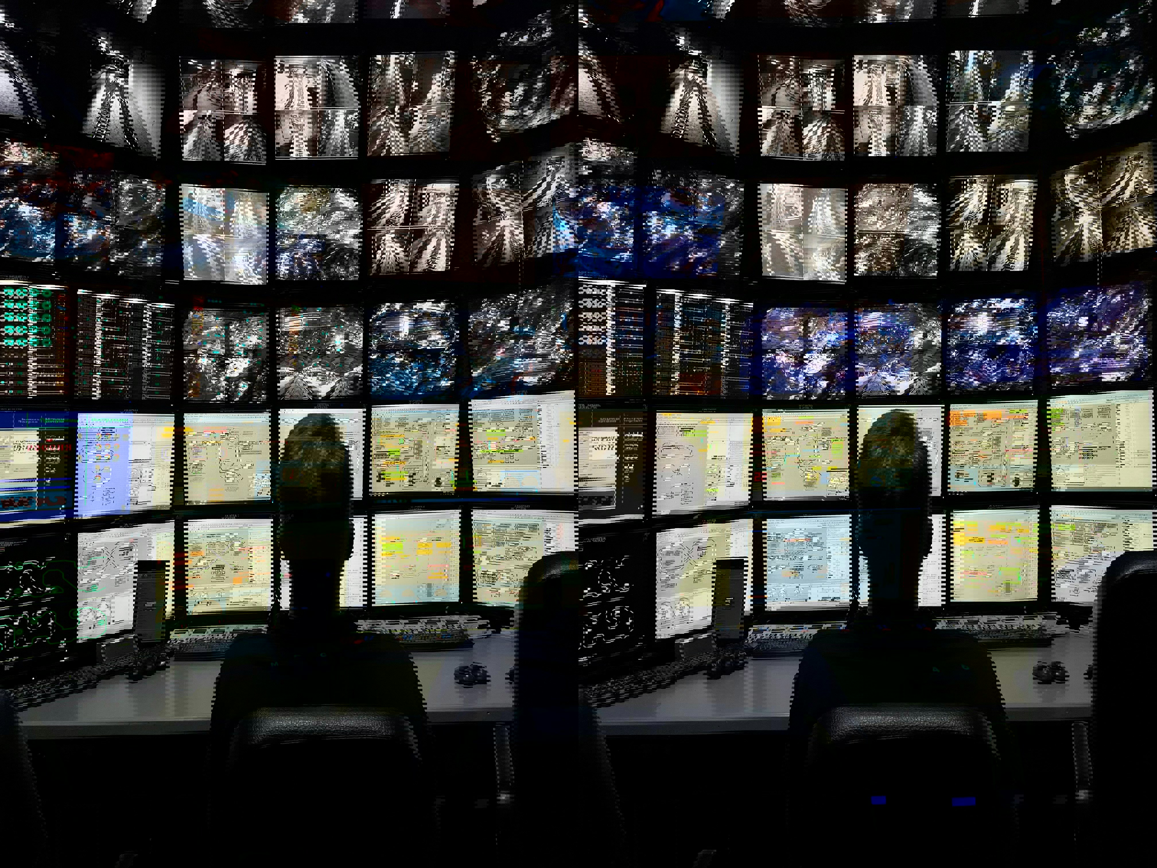 person framför vägg av dataskärmar