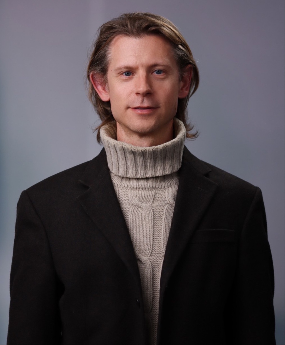 Leende halvkropp i svart kavaj beige polo