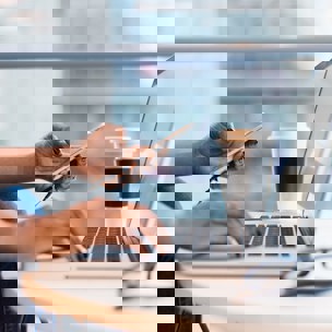 Händer som håller en mobiltelefon och klickar på dator