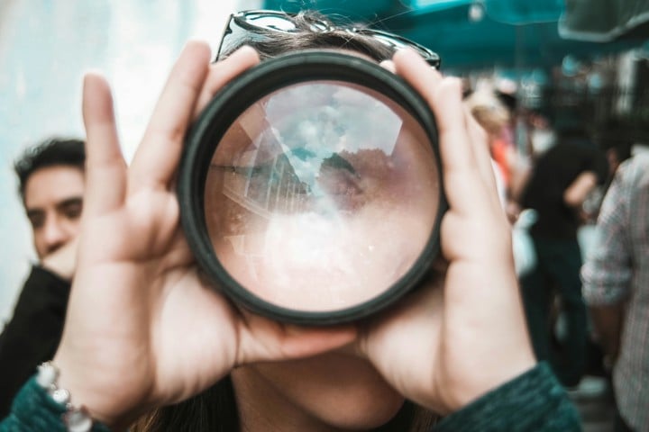 person holding lens in front of face