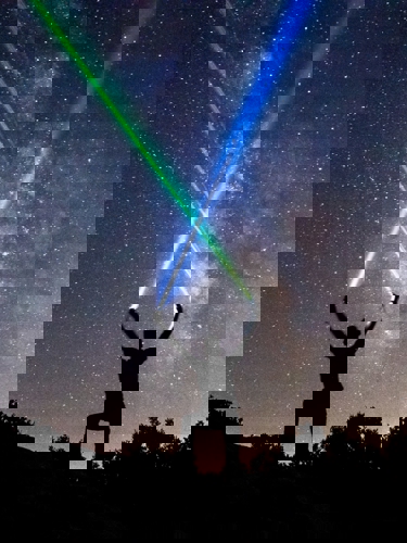 person korsar laserstrålar mot himmel