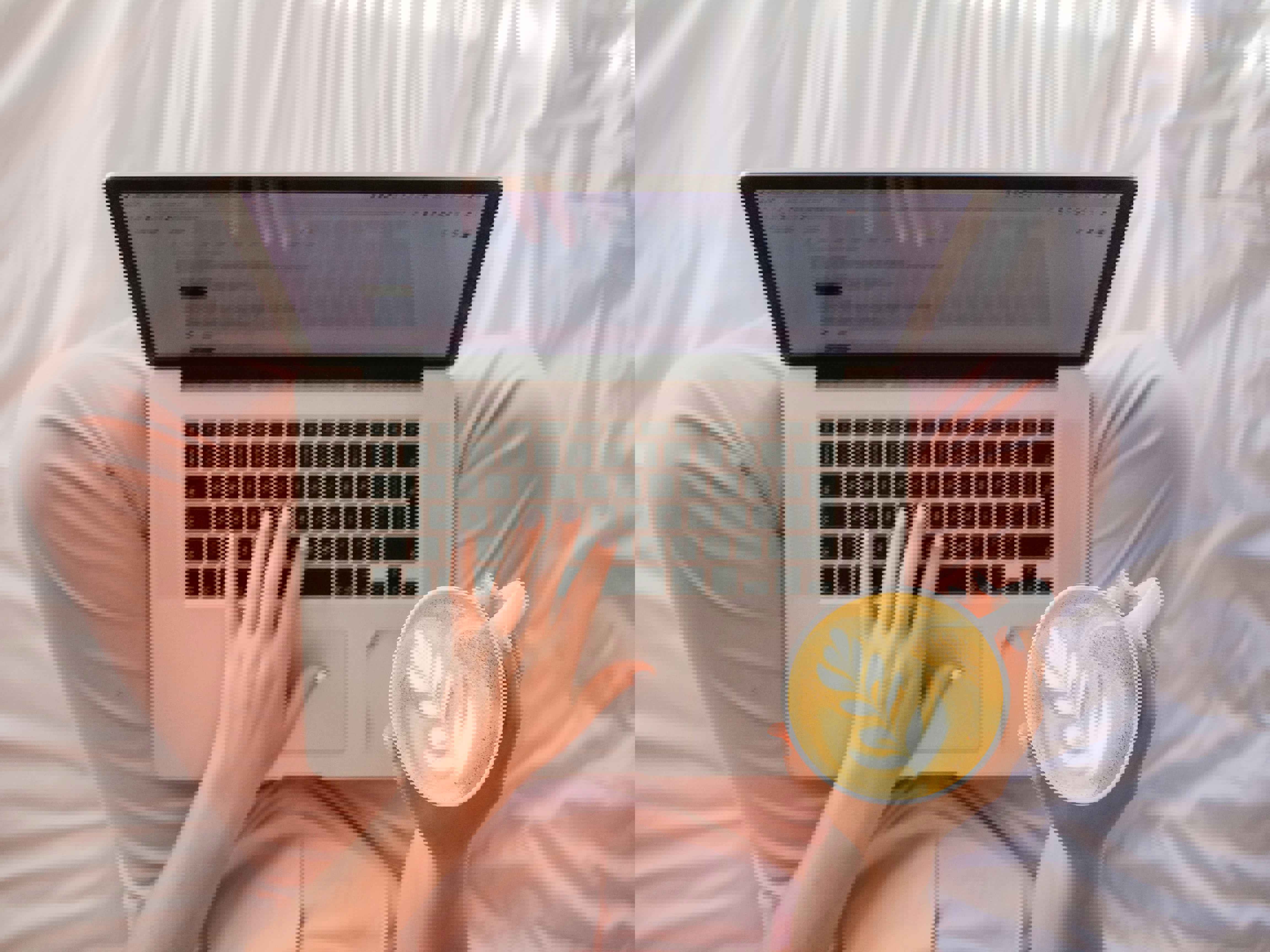 Laptop och kaffekopp i knäet på person med rosa byxor, sedd uppifrån